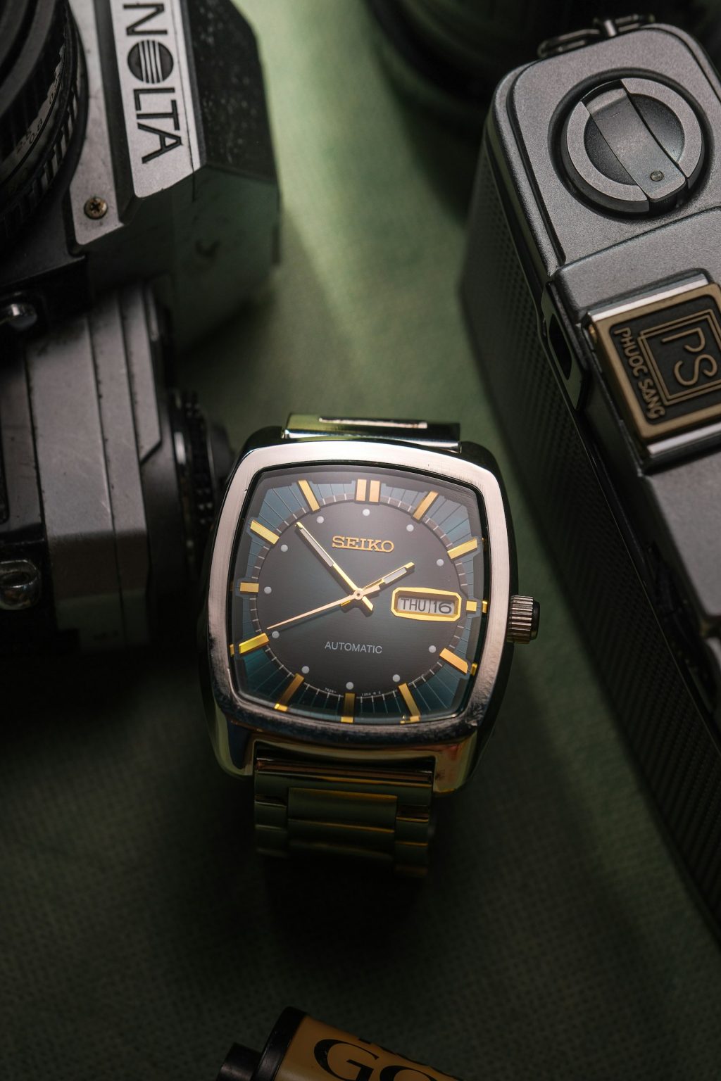Montre Seiko vintage automatique posée parmi des appareils photo anciens